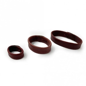 May include: Three brown leather rings of different sizes. The rings are made from soft, supple leather and have a smooth, polished finish.