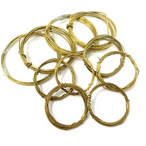 May include: A collection of gold-coloured wire coils, arranged in a circular pattern. The coils are of varying sizes and thicknesses, creating a visually interesting texture.