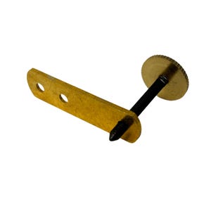 May include: A brass-coloured furniture clamp with a black screw. The clamp has a rectangular base with two holes and a circular head. The screw is threaded and connects the base to the head.