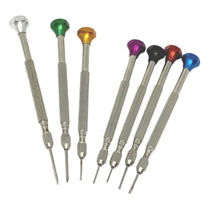 May include: A collection of eight small screwdrivers. Each has a silver handle and a jewel-toned top in colours such as green, yellow, purple, black, red, and blue. These tools are designed for precision tasks.