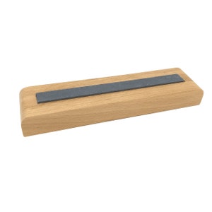 May include: A wooden sharpening block with a grey sharpening stone inset into the top.