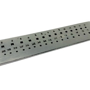 May include: A silver metal ring sizing gauge with a black printed scale from size 1 to 30. The gauge has a Stella logo on the side.