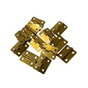 May include: A collection of small, brass-coloured hinges. Each hinge has a rectangular shape with rounded corners and multiple screw holes. The hinges are scattered against a white background, suggesting a hardware or craft supply.
