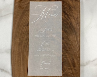 May include: A white menu card with a handwritten script font. The menu includes starters, entrees, and dessert. The starters are vegetarian vegetable and couscous salad. The entrees are filet mignon with green beans and lobster with mashed potatoes. The dessert is creme brulee.