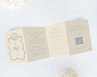 May include: A folded wedding invitation with a seashell design and the initials "R and J". The invitation is beige with blue text and includes details about the wedding date, time, and location. White flowers are in the background.