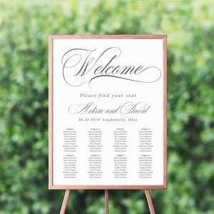 May include: A white wedding seating chart with a black frame and a gold easel stand. The chart has the text "Welcome" in a decorative script font, followed by "Please find your seat" and "Melissa and David". The date "08.20.2019" and location "Loudonville, Ohio" are also included. The chart lists the names of guests assigned to each table.