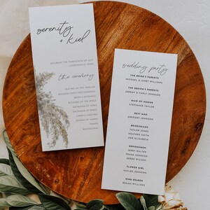 May include: Two white cards with black text on a wooden surface. The first card has the text "serenity + kiel" and the date "Saturday, the thirteenth of July, Loudonville, Ohio". The second card has the text "wedding party" and lists the names of the bride and groom's parents, the maid of honor, the best man, bridesmaids, and groomsmen.