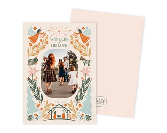 May include: A Christmas card with a family photo inside an oval frame, surrounded by illustrations of angels, stars, and floral elements. The text "Wonders of His Love" is displayed at the top. The card is light pink.