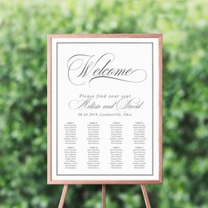 May include: A white wedding seating chart with a black frame. The chart has the text "Welcome" in a cursive font at the top. Below the welcome message, it says "Please find your seat Melissa and David 08.20.2019 Loudonville, Ohio". The chart lists the names of guests assigned to each table.