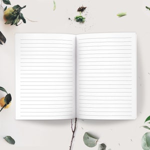 May include: An open lined notebook with white pages, surrounded by small green plants, a pair of scissors, and a wrapped gift box.