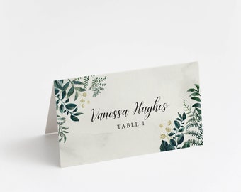 May include: A white place card with a green watercolor floral design. The text "Vanessa Hughes" and "Table 1" is printed in black.