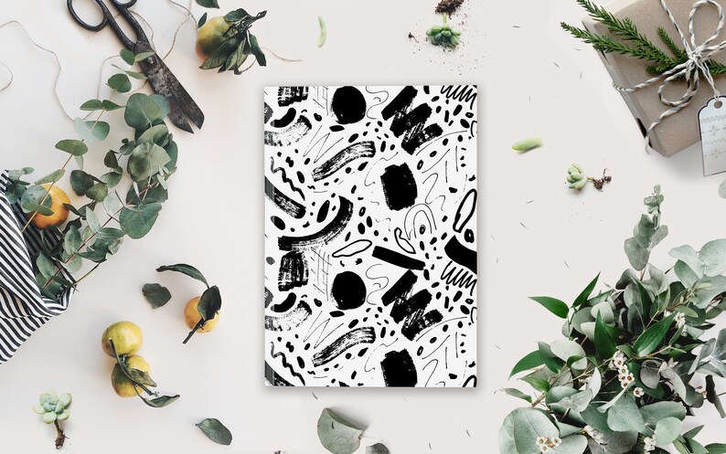 May include: Black and white abstract pattern with brushstrokes and dots on a white background. The pattern is printed on a notebook.