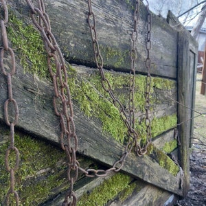 Puede incluir: Estructura de madera envejecida cubierta de musgo verde vibrante, con cadenas de metal oxidadas. La madera muestra signos de edad y exposición, creando una apariencia rústica y texturizada. Las cadenas añaden un elemento industrial contrastante.