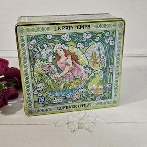 Peut inclure: Une boîte en fer rectangulaire avec un motif floral décoratif et les mots "LE PRINTEMPS" et "LEFEVRE-UTILE". La boîte présente une illustration d'une femme en robe rose entourée de fleurs et de feuillage, avec une bordure verte et dorée.
