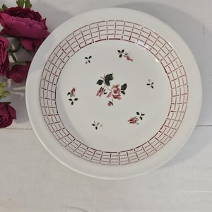 Puede incluir: Plato de cerámica blanca con borde de patrón de ladrillo rojo y detalles florales. El plato presenta un diseño floral central y pequeñas ramitas florales. Una pieza decorativa para servir o exhibir.