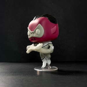 Op de afbeelding: Een roze en witte pop vinyl figuur van een superheld met zwart haar en een wit en grijs kostuum. De figuur houdt een wit en grijs wapen in zijn rechterhand.