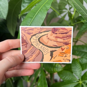May include: A sticker with a colorful illustration of Canyonlands National Park, featuring a winding canyon and the text "Canyonlands National Park".