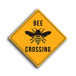 Può includere: Segnale stradale giallo a forma di diamante con un'illustrazione di ape nera e le parole "BEE CROSSING". L'ape ha un motivo a nido d'ape sul corpo e sulle ali.