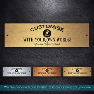 Op de afbeelding: Een rechthoekig metalen plaatje met een geborstelde afwerking, verkrijgbaar in goud-, zilver- en kopertinten. Het plaatje bevat de zwarte tekst CUSTOMISE WITH YOUR OWN WORDS! en een vulpenpictogram. Het heeft twee kleine montagegaten.
