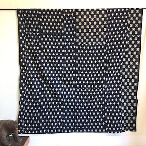 May include: A dark blue and white textile with a patchwork design. The textile is made up of squares with different patterns, including polka dots and a crosshatch pattern.