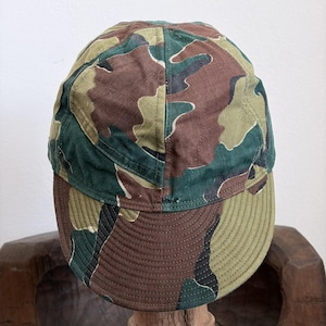 Puede incluir: Gorra de béisbol de camuflaje en tonos verdes, marrones y beige. La gorra tiene una visera curva y una corona estructurada. La tela presenta un patrón moteado y la gorra parece estar hecha de un material duradero.