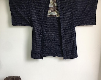 Op de afbeelding: Een donkerblauw Japans "Hanten"-jack met een wit stippenpatroon. Het jack heeft een bloemenprint voering.