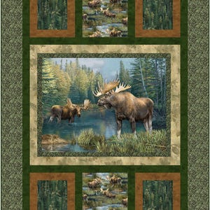 May include: A rectangular quilt featuring a central panel of two moose standing in a forest lake. The design includes smaller square panels with moose motifs, surrounded by dark green and brown fabric borders with forest and leaf patterns.