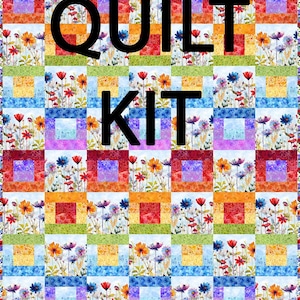 May include: A colorful quilt kit featuring a floral pattern with the words "QUILT KIT" in large black letters. The quilt design includes squares of various colors, including red, orange, blue, and purple, with a floral print.