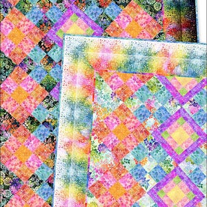 May include: Two colorful quilts with a diamond pattern. The quilts feature squares of various colors, including pink, orange, blue, and green, with floral and abstract designs. The edges have a rainbow gradient.