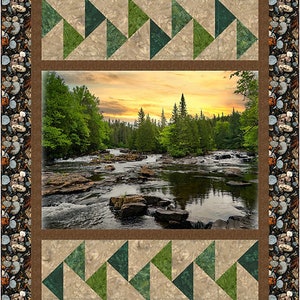 May include: A decorative quilt featuring a scenic river landscape with a sunset sky. The quilt has a border of pebbles and a geometric pattern of green and tan triangles. The central image depicts a river flowing through a forest.