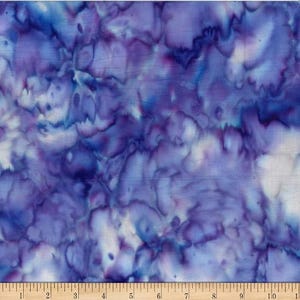 May include: A close-up of fabric with a tie-dye pattern in shades of blue, purple, and white. The fabric has a watercolor effect, with the colors blending and swirling together. A ruler is at the bottom of the image.