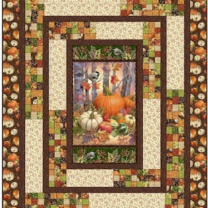 May include: A quilt with a fall theme featuring a central panel with pumpkins, gourds, and birds in a forest setting. The panel is surrounded by a brown frame and multiple layers of patchwork fabric in shades of brown, green, cream, and orange.