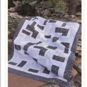 May include: A white and black quilt with a geometric pattern. The quilt is folded and lying on a stone surface. The text "Stacks and Strips" and "Quilting Renditions" is visible on the image.  My Design...Your Beautiful Rendition.