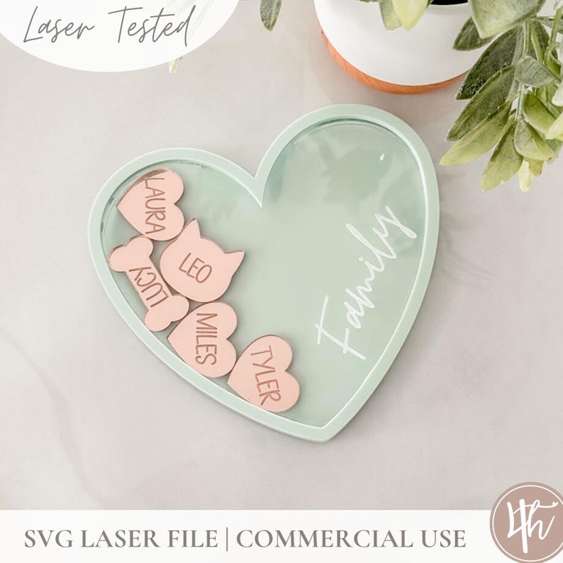 May include: A light green heart-shaped tray with the word "Family" written on it. Inside the tray are five pink heart-shaped pieces with the names "Laura", "Leo", "Lucy", "Miles", and "Tyler" written on them.