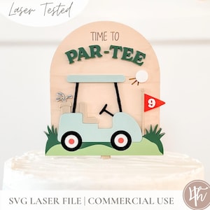 May include: A wooden cake topper with a golf theme. The topper features a light blue golf cart, a golf ball, and a red flag with the number 9. The text "TIME TO PAR-TEE" is displayed in green. The words "Laser Tested" and "SVG LASER FILE | COMMERCIAL USE" are also visible.