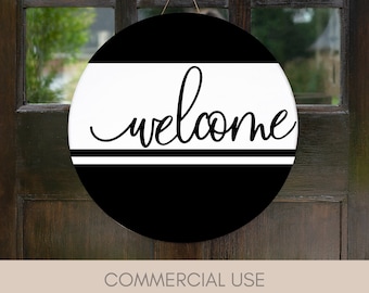 May include: Black and white round welcome sign with the word "welcome" written in a cursive font. The sign is hanging on a wooden door.