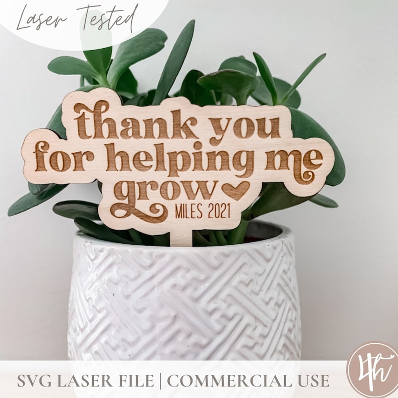 May include: A wooden plant stake with the text "thank you for helping me grow" and a heart symbol. The text "MILES 2021" is also included on the stake.