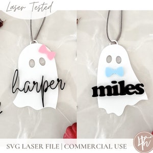 May include: Two white ghost ornaments with black lettering. One ghost has a pink bow and says "harper" and the other ghost has a blue bow tie and says "miles".