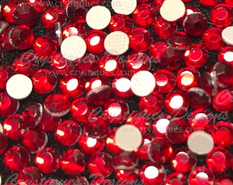 May include: Close-up of red and white rhinestones. The rhinestones are scattered on a black surface. The rhinestones are small and round. The rhinestones are shiny and reflective. The rhinestones are used for crafting and decorating.