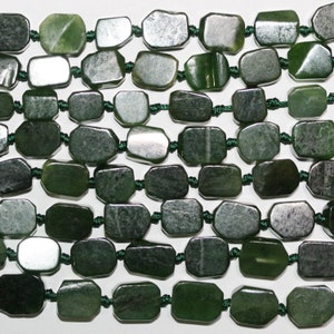 May include: A necklace featuring rectangular jade beads in shades of green, strung together with dark green cord. The polished beads have a smooth, reflective surface. The necklace is displayed against a white background, highlighting the jade's colour.