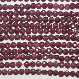 May include: A strand of pink gemstone beads with a faceted finish. The beads are round and have a slightly irregular shape. The beads are strung on a clear thread.