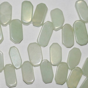 May include: A strand of light green, opaque, rectangular-shaped beads with a slightly iridescent finish.