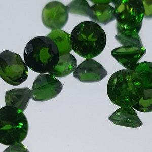 Puede incluir: Una colección de piedras preciosas verdes sueltas, probablemente peridoto o esmeralda, en varios tamaños y formas. Las piedras están facetadas y tienen un color verde brillante y vibrante.