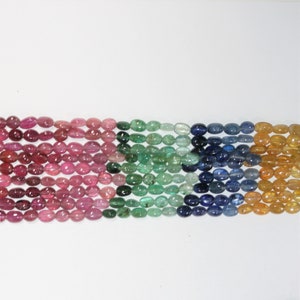 May include: A strand of oval-shaped gemstone beads in various colours, including pink, green, blue, and yellow.