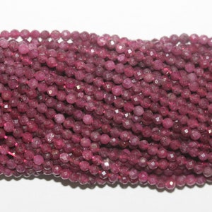 May include: Strands of faceted, round, deep magenta-coloured beads. The beads are strung together, creating a textured surface. The beads are likely gemstones, suitable for jewellery making.