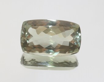 May include: A light green cushion-cut gemstone with a faceted surface.