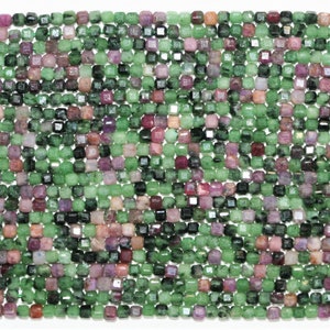 Może przedstawiać: Szereg zielonych i różowych koralików z kamieni szlachetnych, każdy koralik ma kwadratowy kształt z fasetowanym wykończeniem.