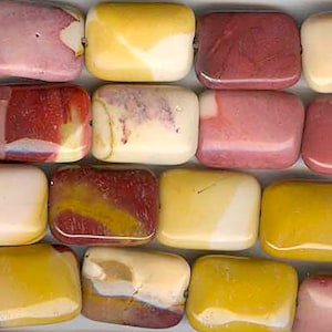 Op de afbeelding: Een streng kleurrijke, rechthoekige, gepolijste stenen kralen. De kralen zijn een mix van rood, geel en wit.