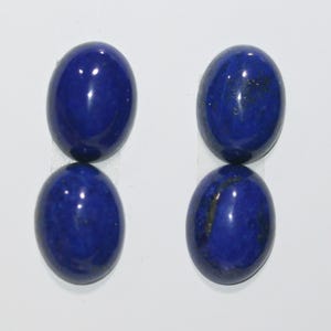 Op de afbeelding: Vier ovale, gepolijste lapis lazuli edelstenen. De stenen hebben een diepe, rijke blauwe kleur met een glad, reflecterend oppervlak. Ze zijn gerangschikt in twee paren, elk paar verticaal gestapeld.