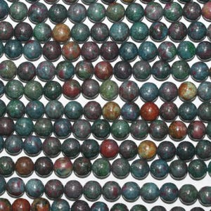 Può includere: Primo piano di perline rotonde in varie tonalità di verde, rosso e marrone. Le perline hanno una finitura lucida e sono disposte a griglia. Adatte per la creazione di gioielli e artigianato, ogni perlina misura circa 8 mm.